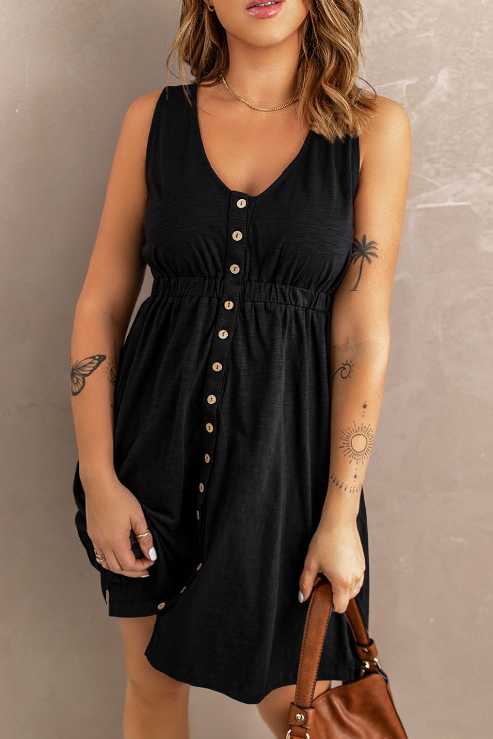 Sleeveless mini dress in dark black with V neckline, button front, and elastic waist
