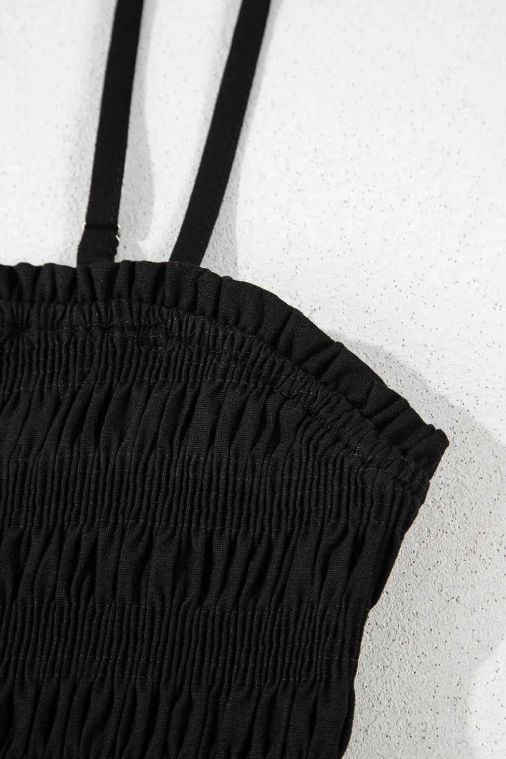 Black smocked wide-leg jumpsuit close-up of tiered ruched bodice and waistband