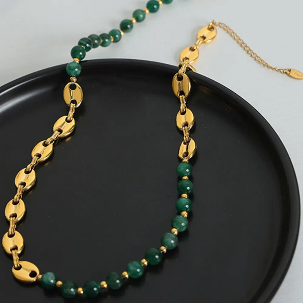 Gold beaded necklace with green round beads and oval link sections on a chain