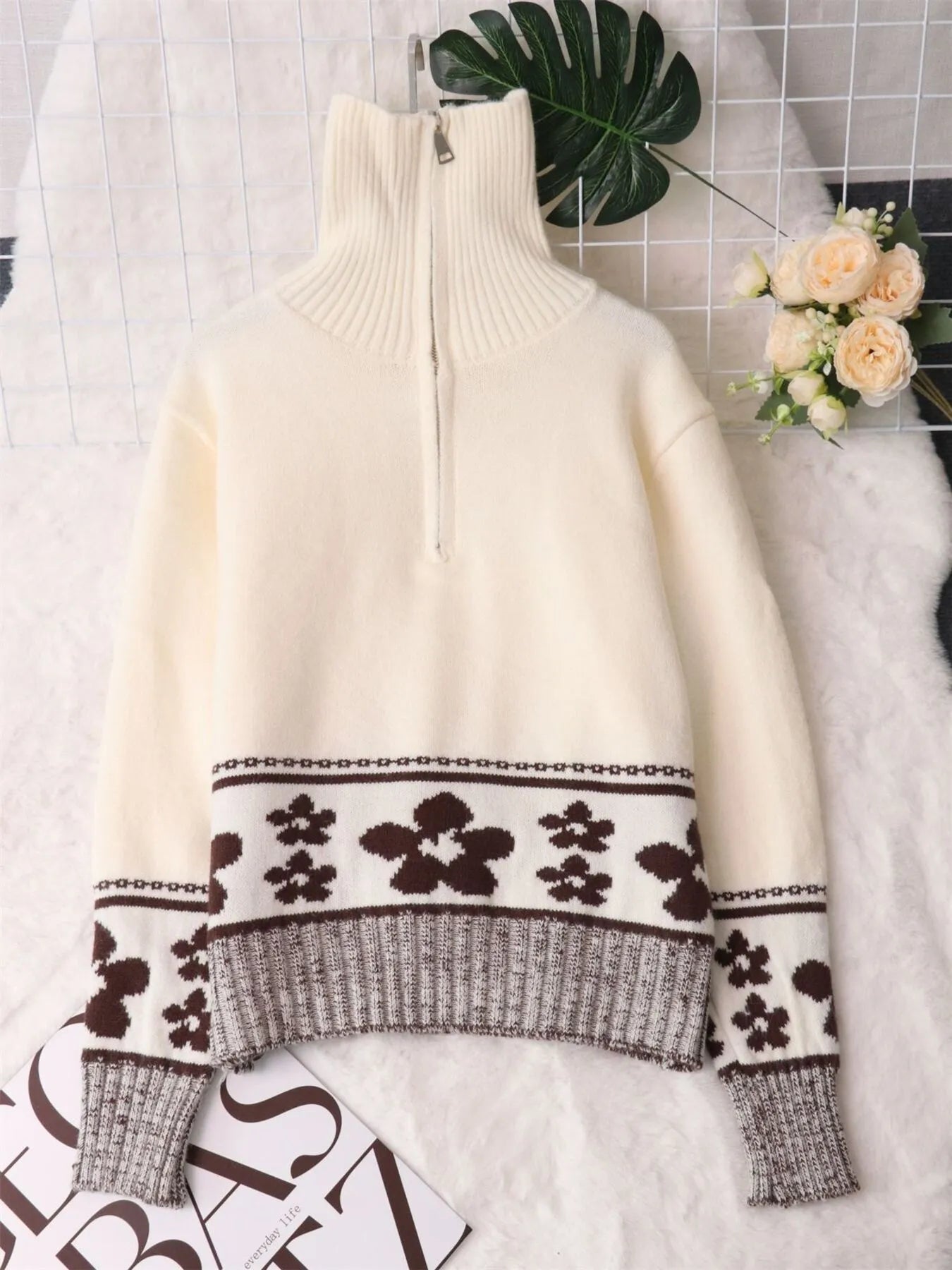 Cream sleeved sweater with stand collar and half-zip, featuring a black flower knit band