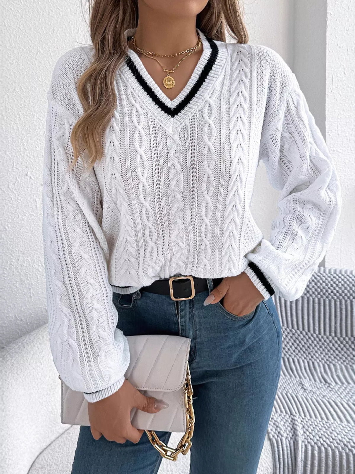 White V-neck cable knit sweater with black trim, ribbed cuffs and hem
