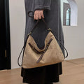 Tan suede shoulder bag with decorative buckle and gold-tone hardware, open top