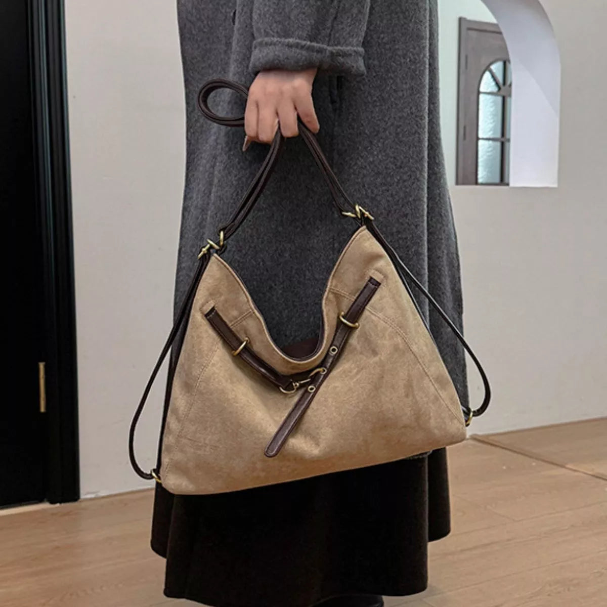 Tan suede shoulder bag with decorative buckle and gold-tone hardware, open top