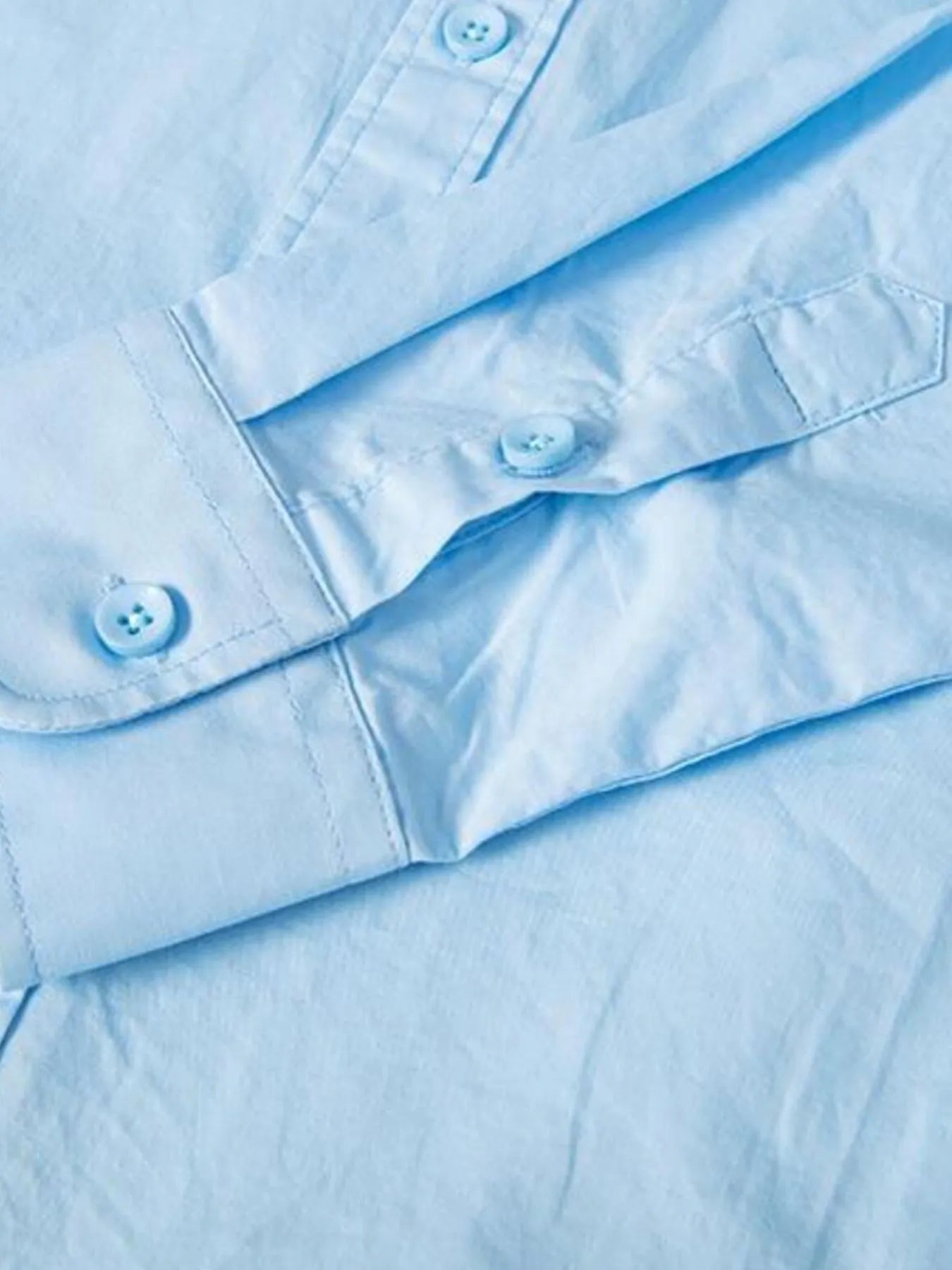 Light blue button-up shirt front placket and cuffs with visible buttons and seams