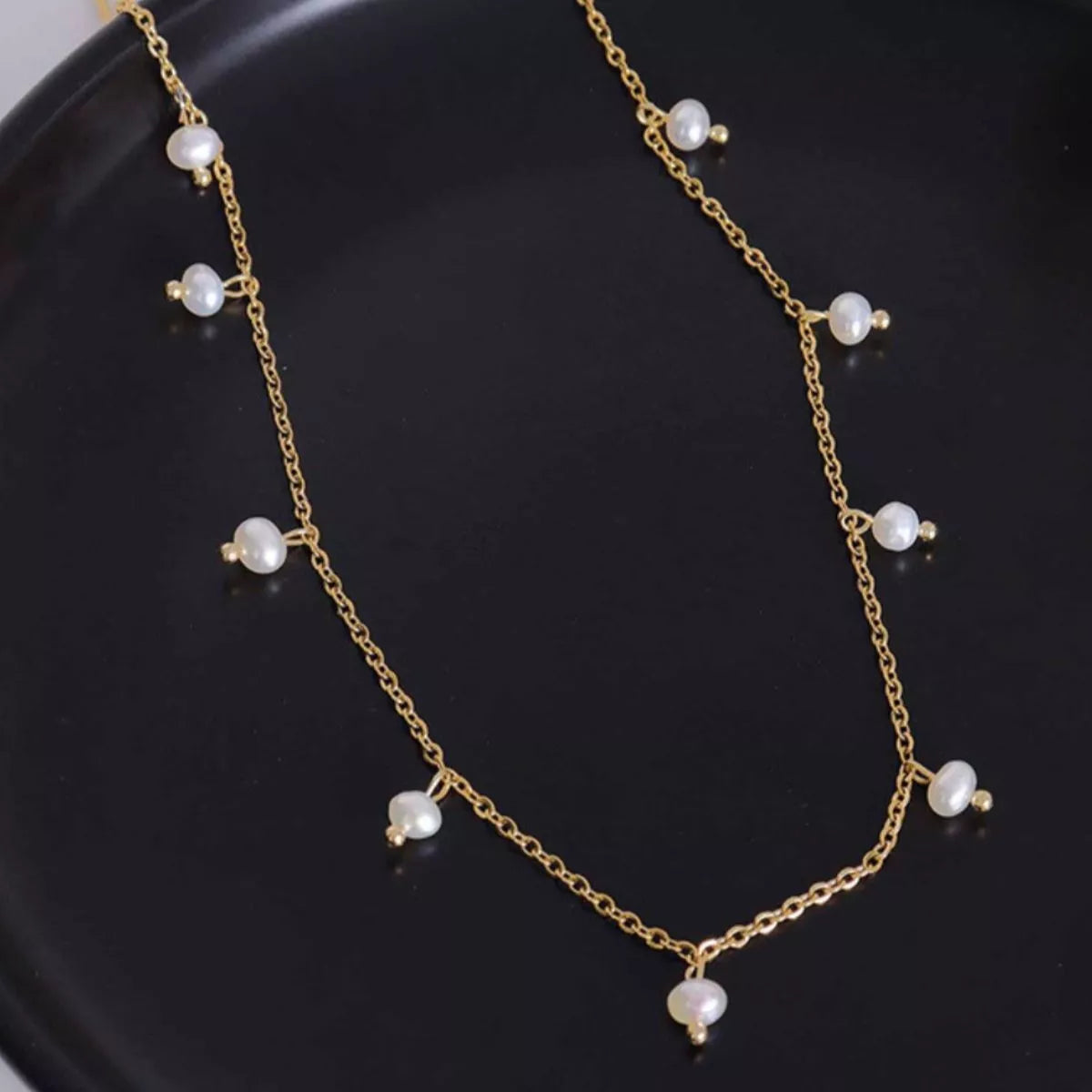 Gold-plated pearl necklace with multiple small freshwater pearls on an oval chain