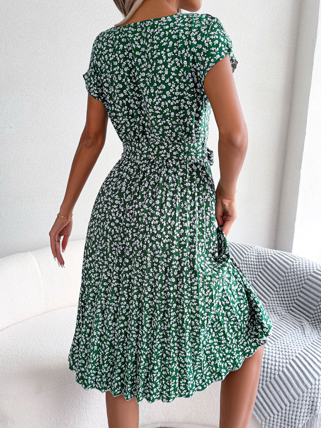 Green ditsy floral pleated belted dress with short sleeves, back view