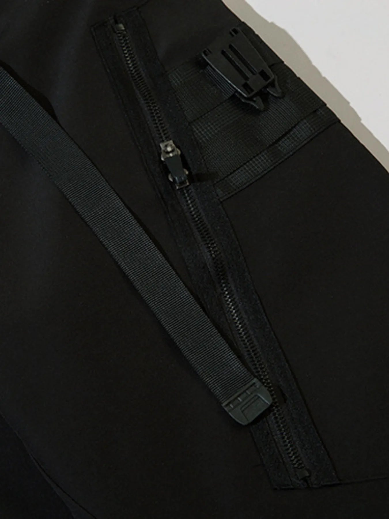 Black cargo joggers close-up of thigh pocket with zip closure and strap