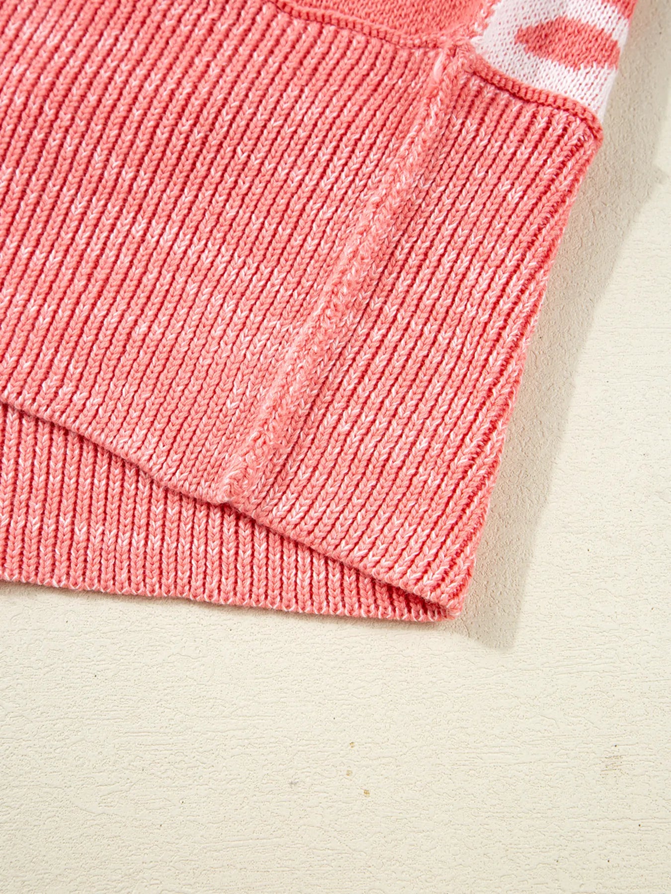 Burnt coral knit sweater close-up showing ribbed hem and side of checker snowflake pattern