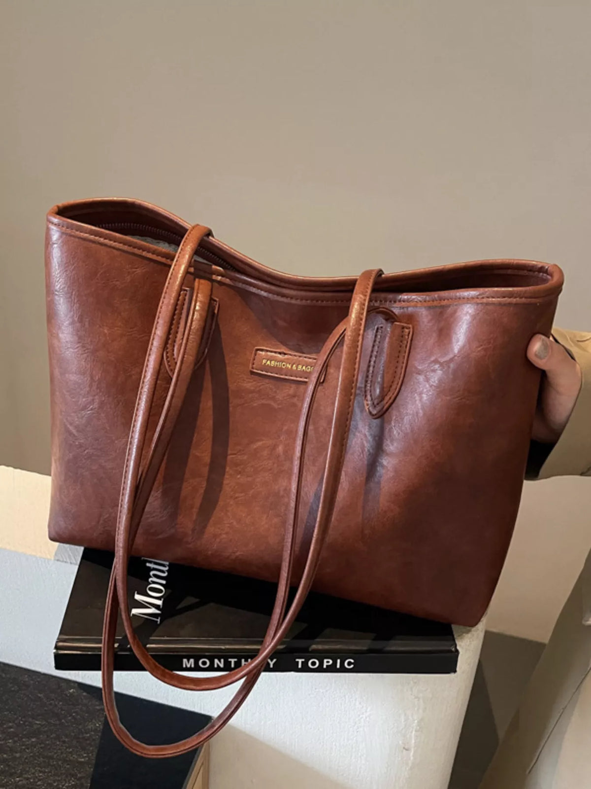 Brown vegan leather tote bag with long shoulder handles and front pocket panel
