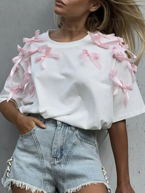 White short sleeve T-shirt with pink bow ribbon accents on the shoulders