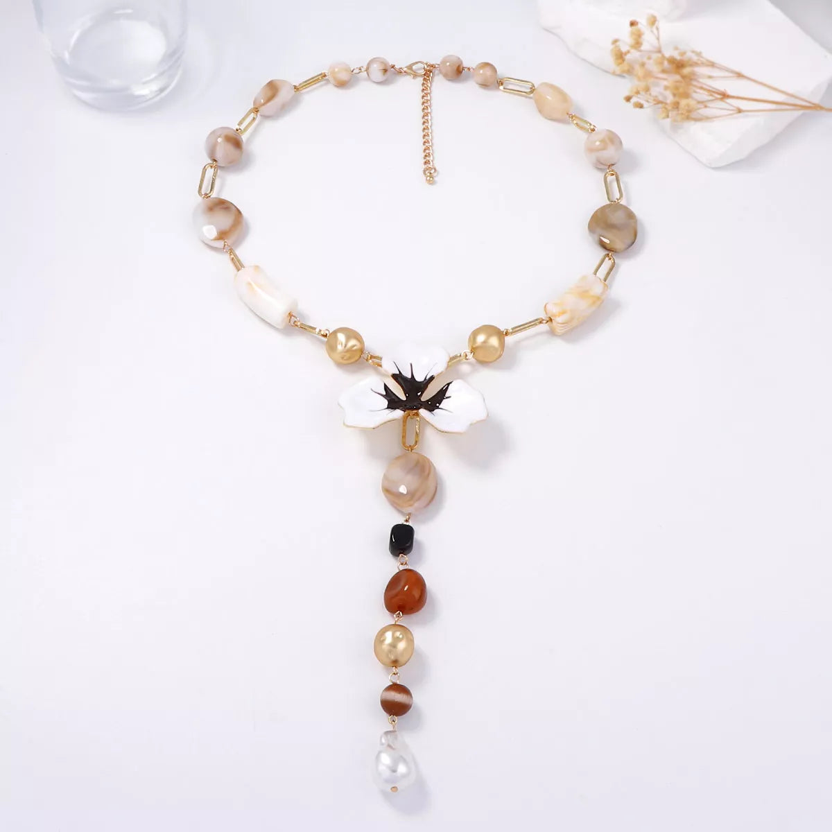 Y-shaped necklace on display with white flower pendant and dangling bead drops