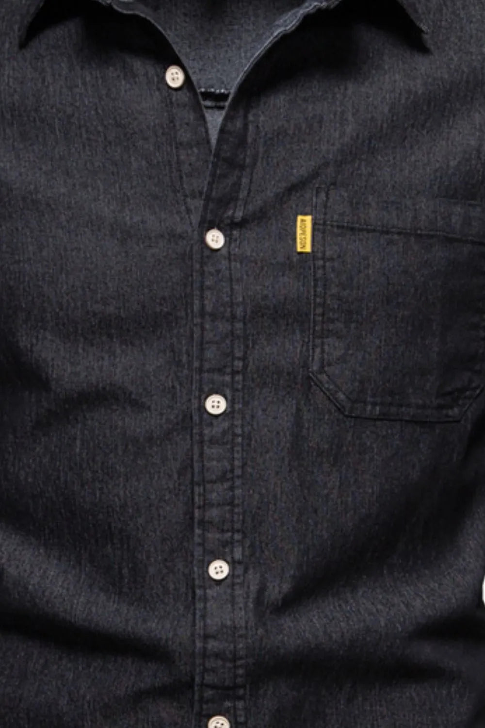 Black denim button-up shirt closeup of placket, buttons, and chest pocket