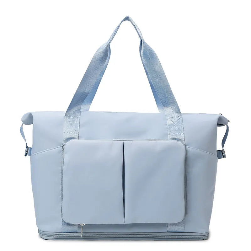 Light blue travel duffel bag with front organizer pocket, top handles, and side carry straps.