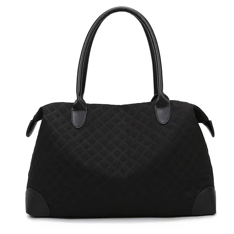 Black quilted travel bag with top handles, side pulls, and zip closure