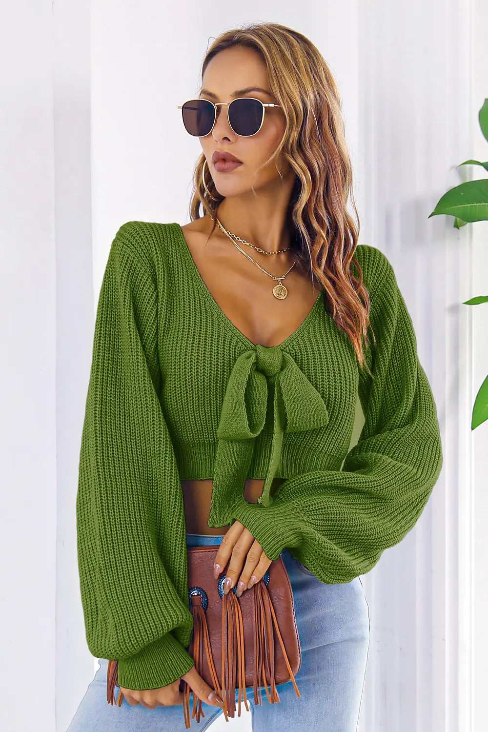 Green knit cropped sweater with long sleeves, V-neck and front bow detail.