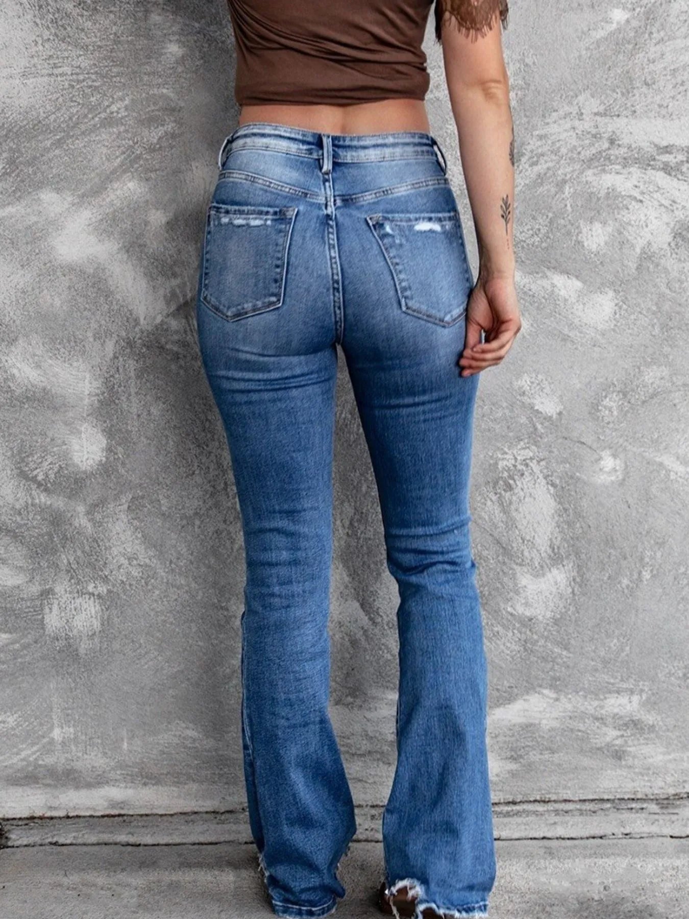 Light blue distressed flare jeans with stacked front knee rips and back patch pockets