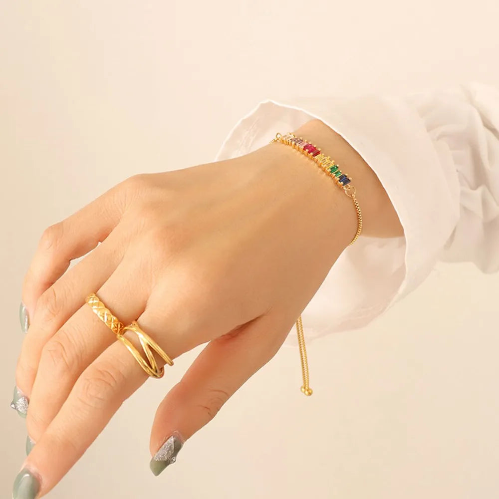 Multicolor zircon bracelet with thin gold chain on a bare wrist