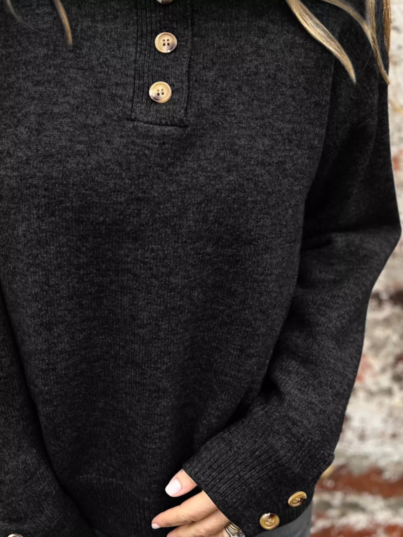 Black knit sweater with long sleeves and ribbed cuffs with wood-tone button detail