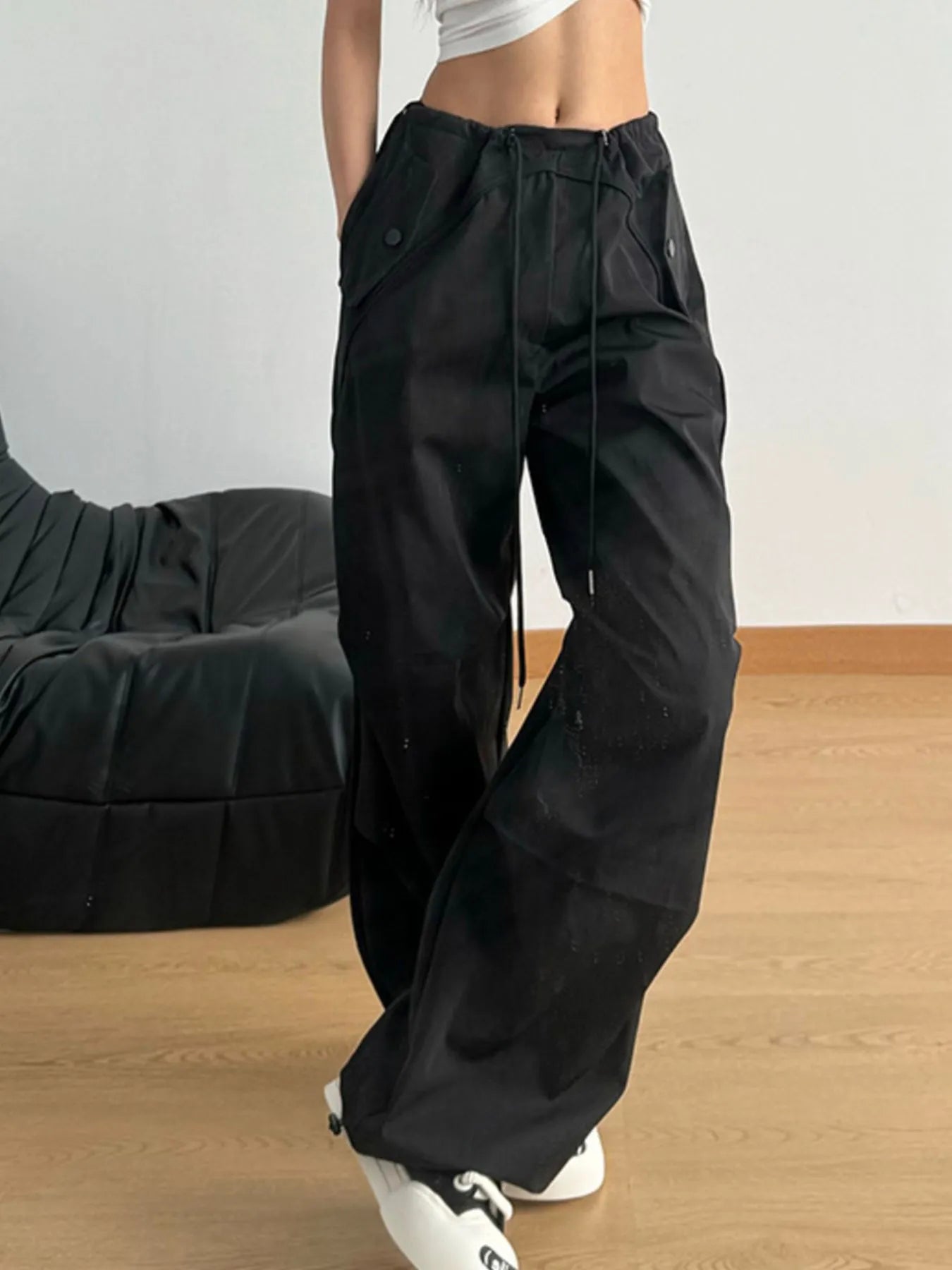 Black wide-leg drawstring pants with elastic waistband and cargo-style pocket seams