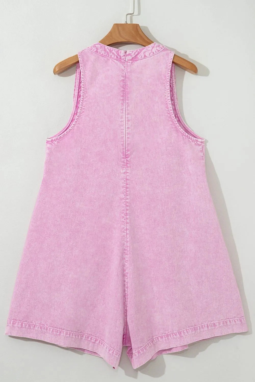 Pink mineral-wash sleeveless denim romper with button placket at back and yoke seam