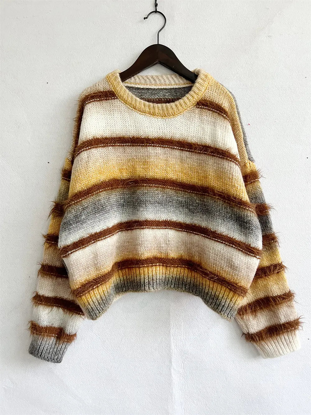 Striped round-neck sweater on a hanger in cream, brown, and gray horizontal stripes