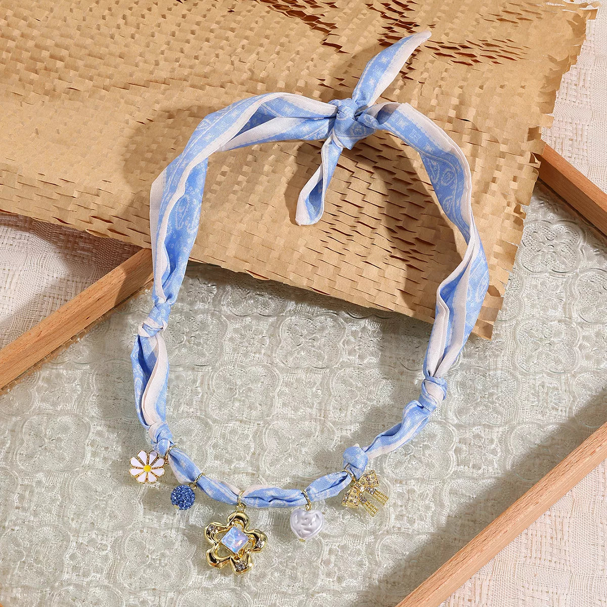 Light blue ribbon charm necklace with gold flower charm and dangling crystal beads