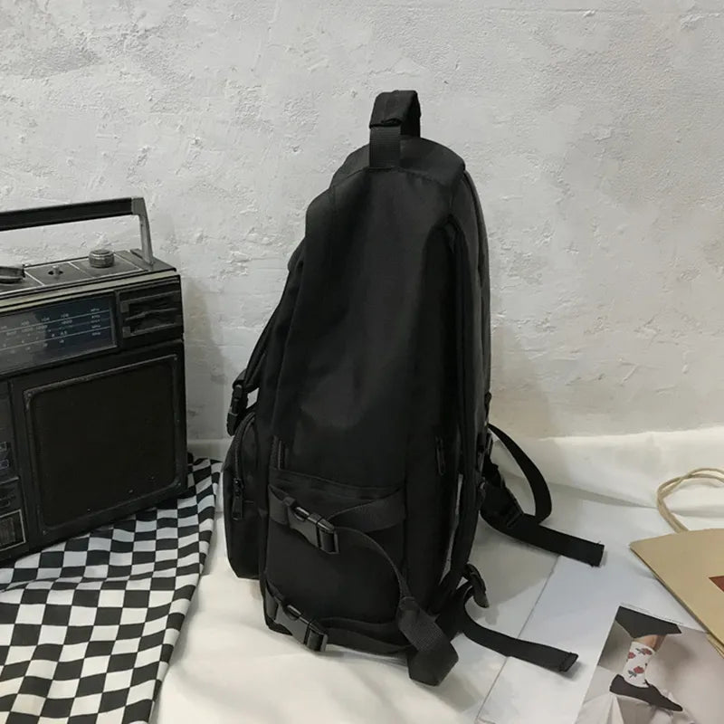 Black backpack side view with adjustable straps and front pocket detail
