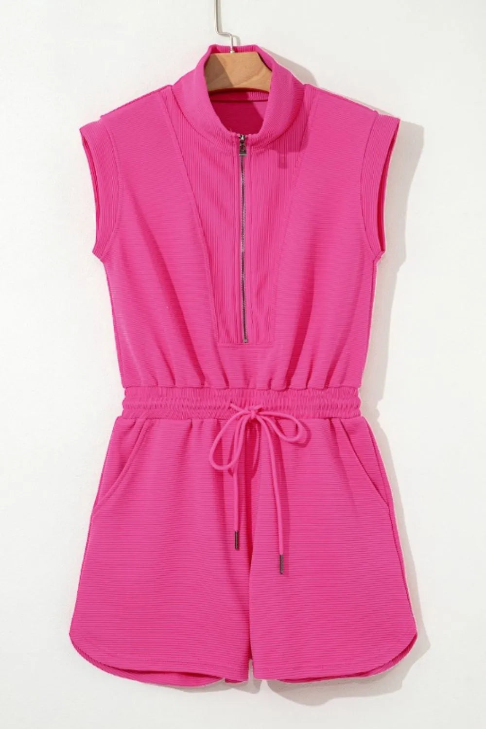 Hot pink textured short romper on hanger, half-zip front with drawstring waist ties