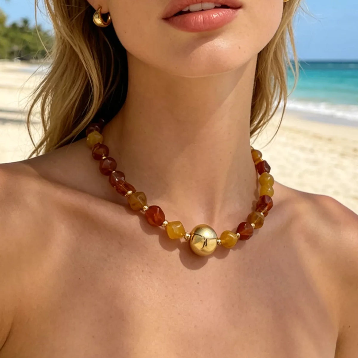Gold-tone beaded statement necklace with round center charm and warm amber bead strand