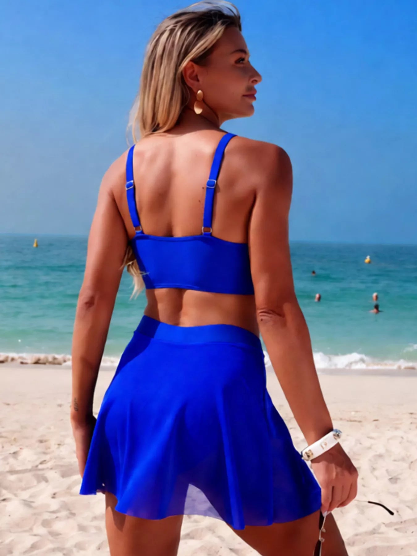 Twist Front Cami and Skort Swim Set in royal blue, back view on beach with adjustable straps.