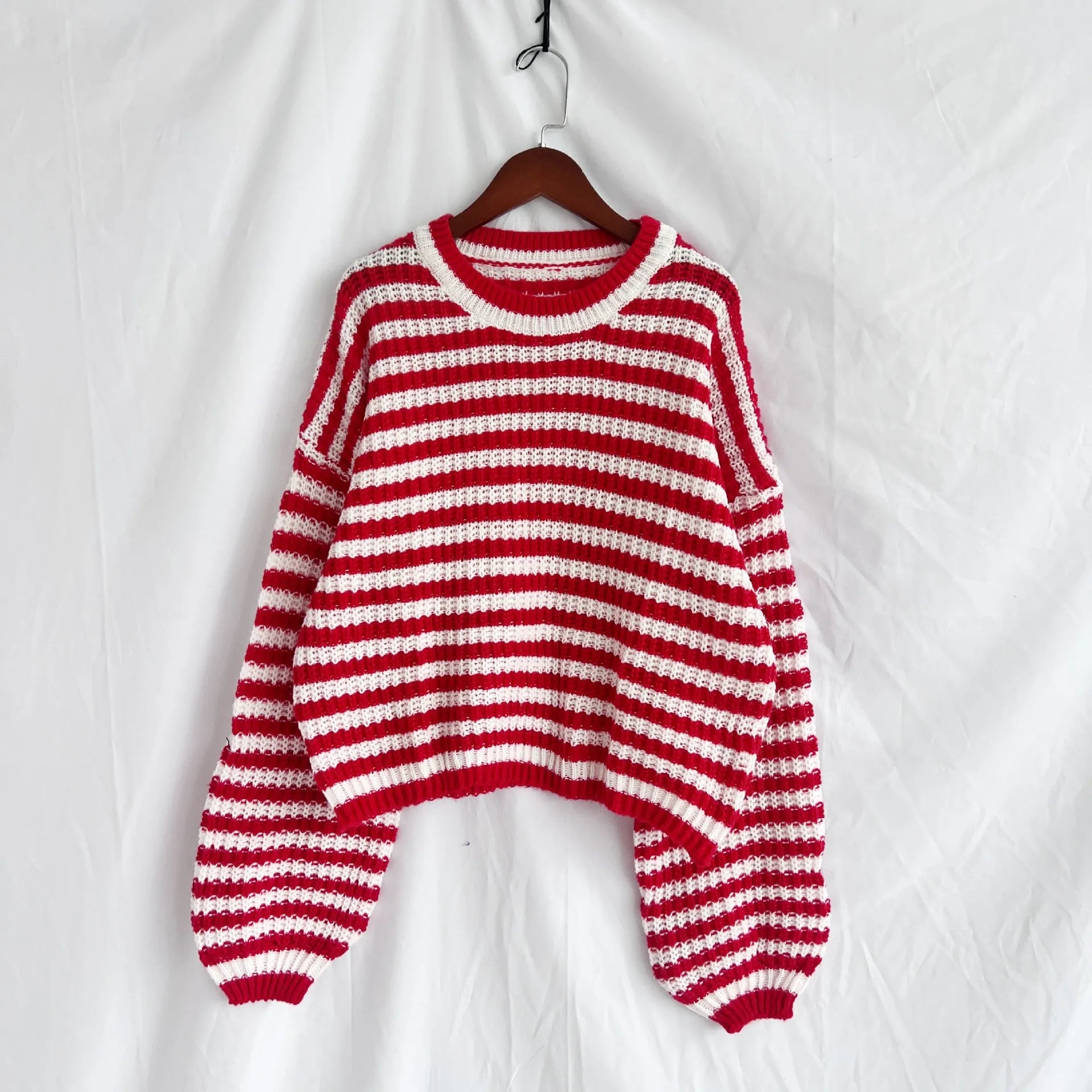 Red-and-white striped oversized knit sweater hanging on a wooden hanger