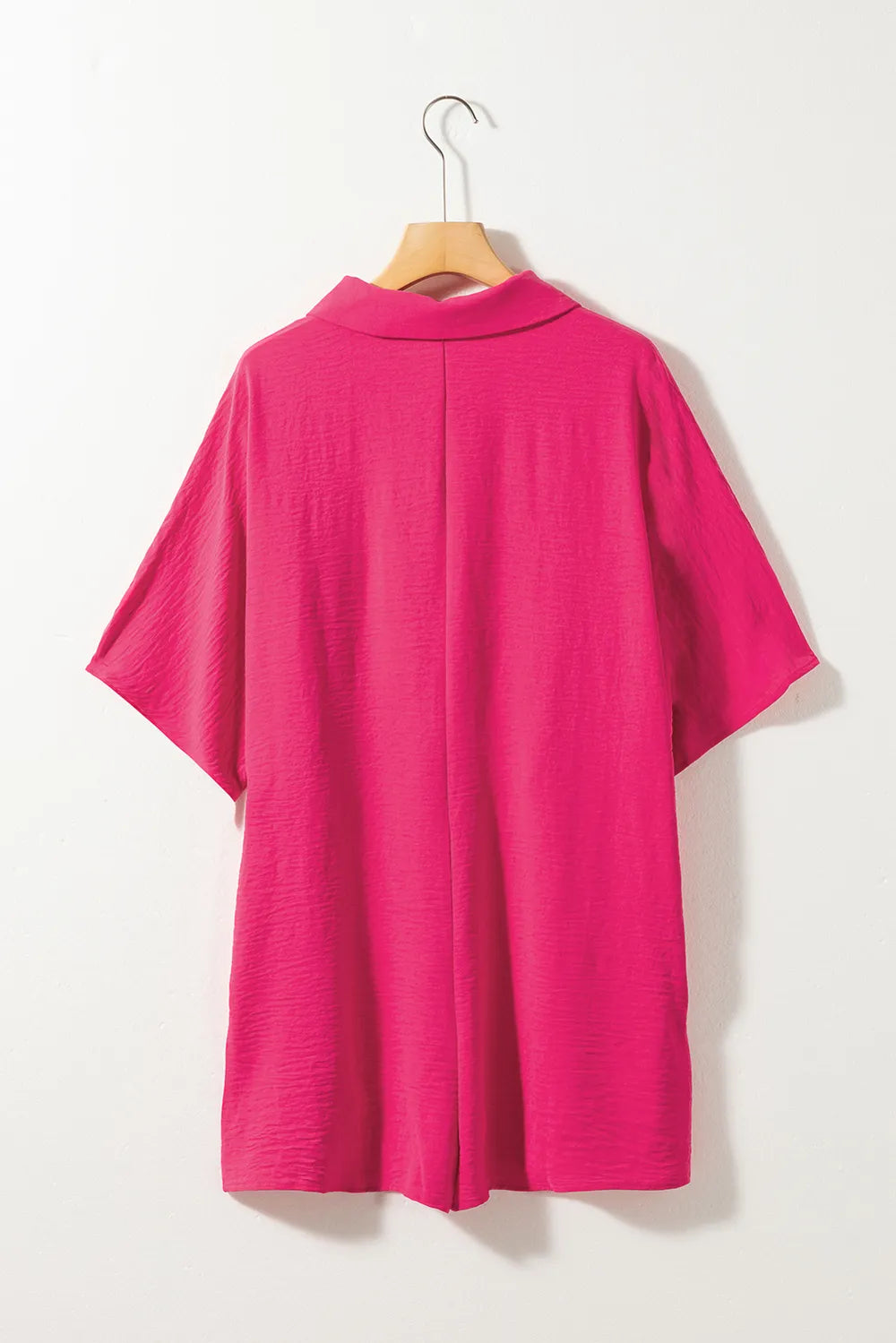 Hot pink half-button collared neck romper on hanger, back view