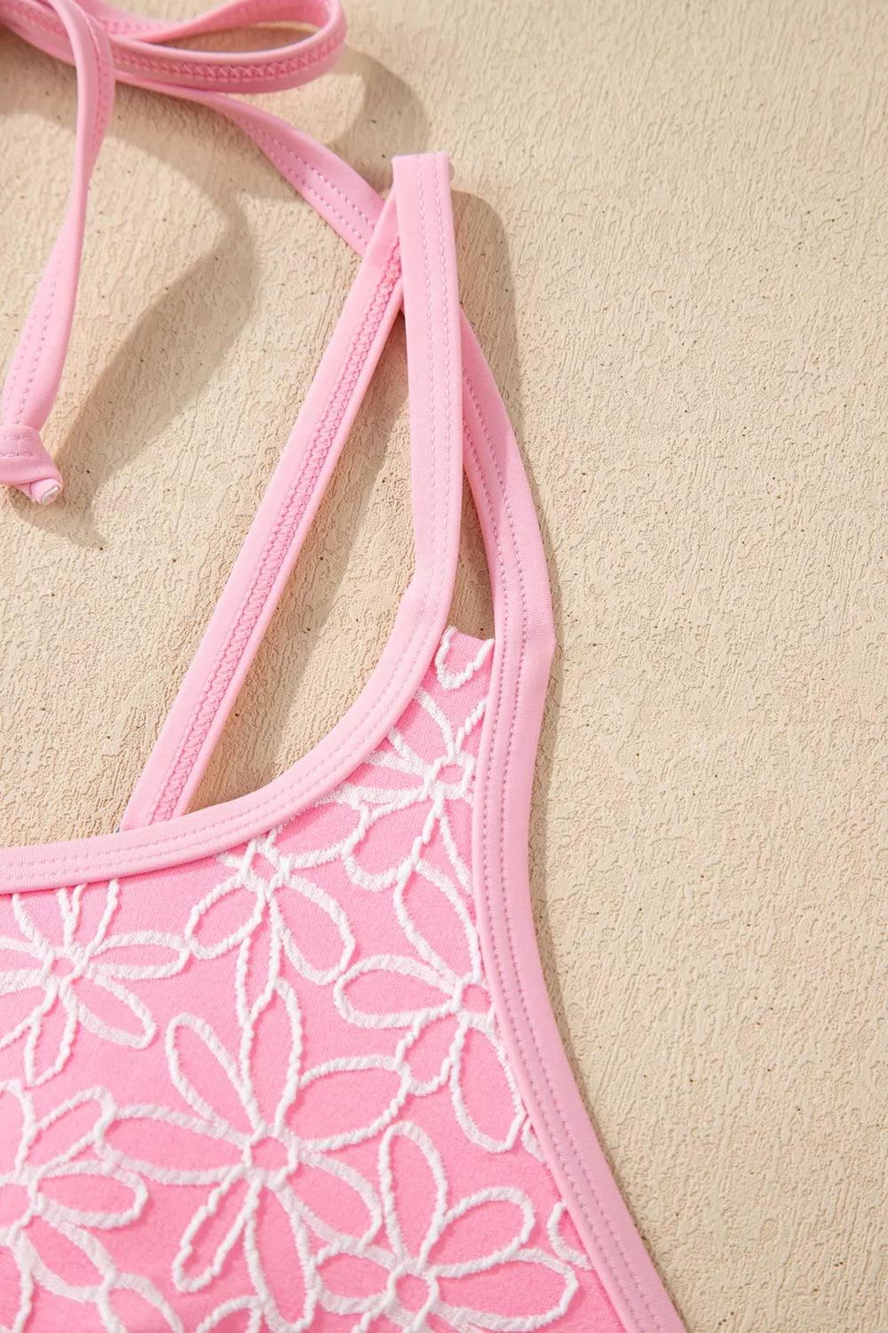 Blush pink halter one-piece swimsuit with floral pattern and side strap detail