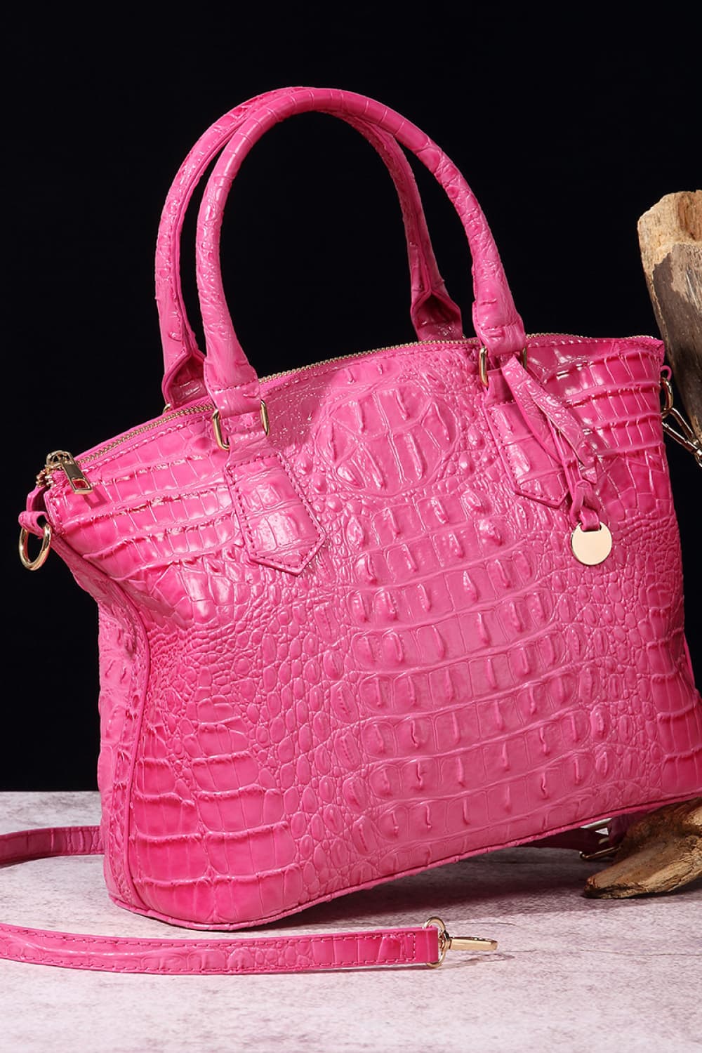 Croc-embossed vegan leather handbag in bright pink with top handles and front emblem