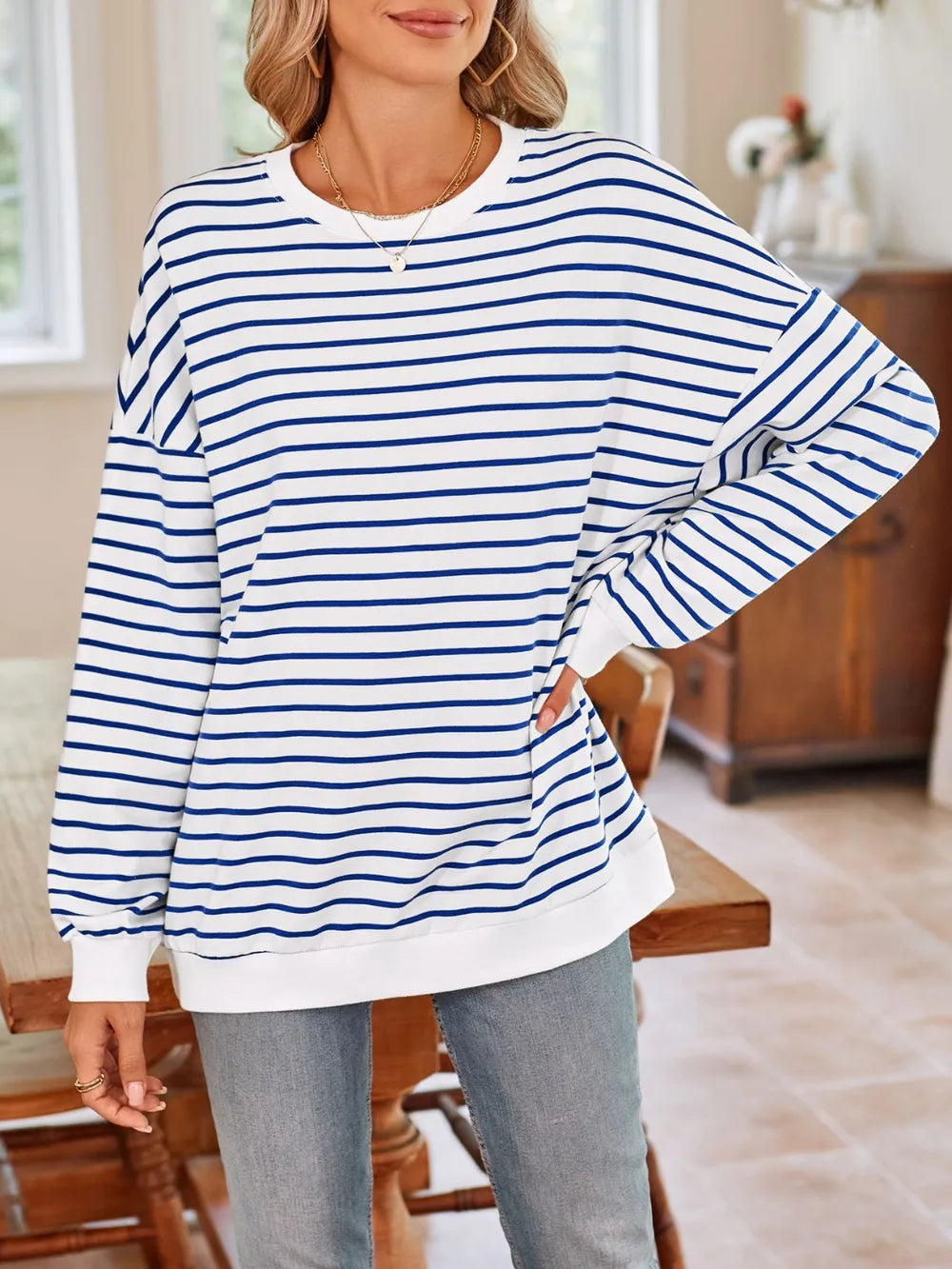 White base sweatshirt with blue striped pattern, round neck long sleeves, angled pose