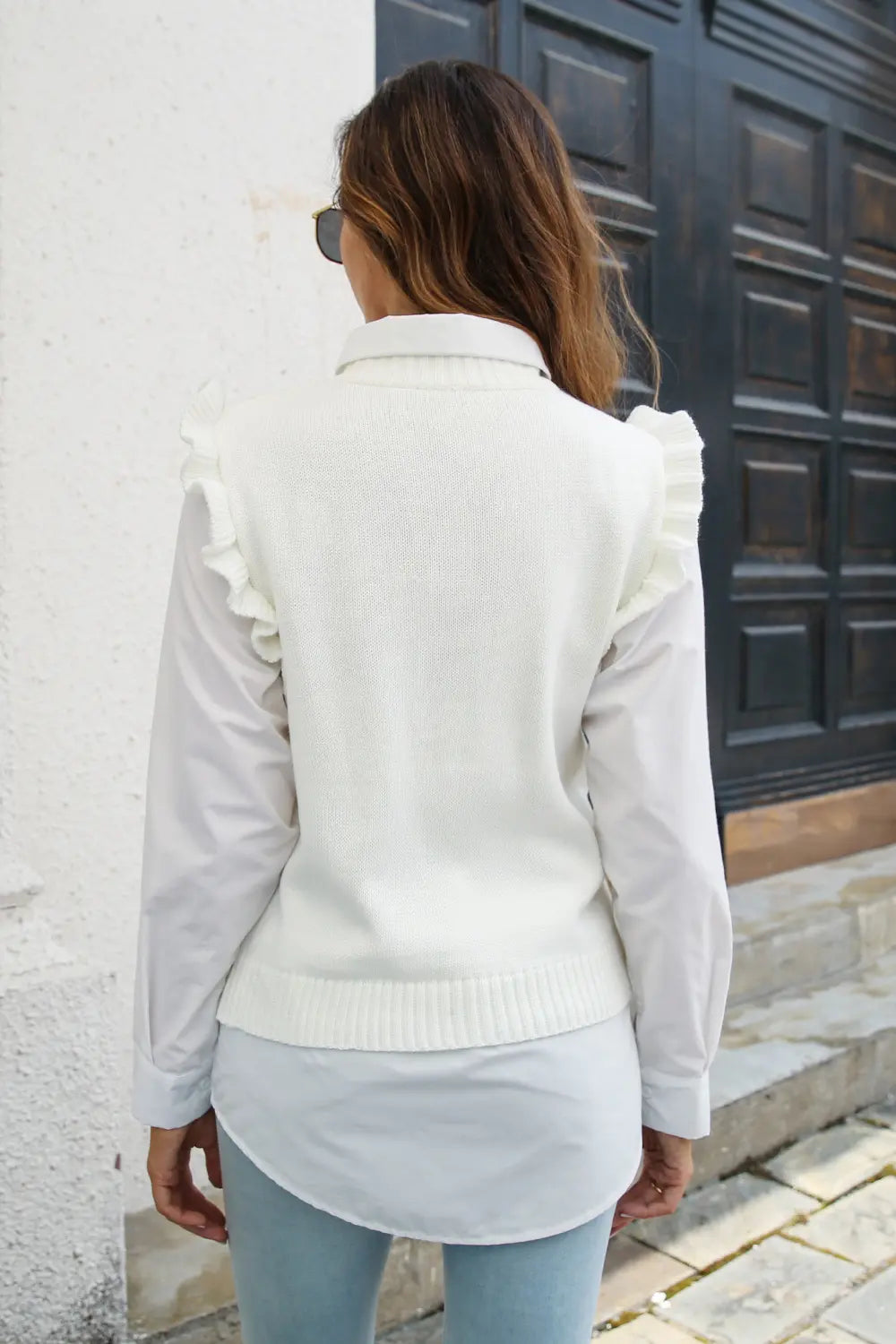 White sleeveless sweater vest, back view, with ruffled shoulder details and ribbed hem