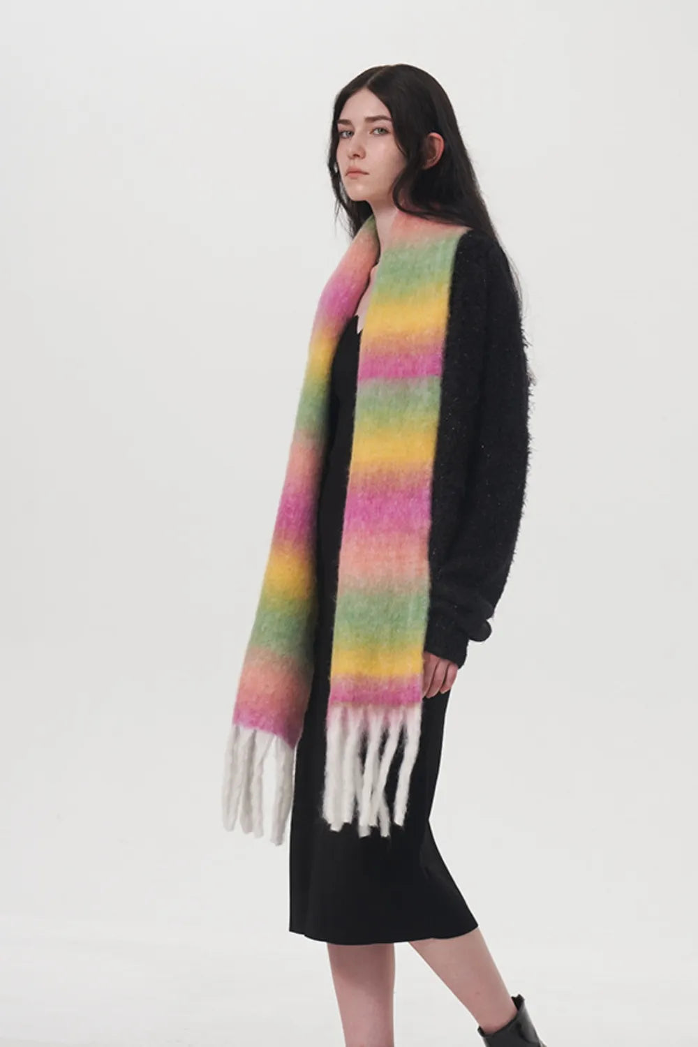 Rainbow gradient thermal scarf with fringed ends, worn over a dark outfit.