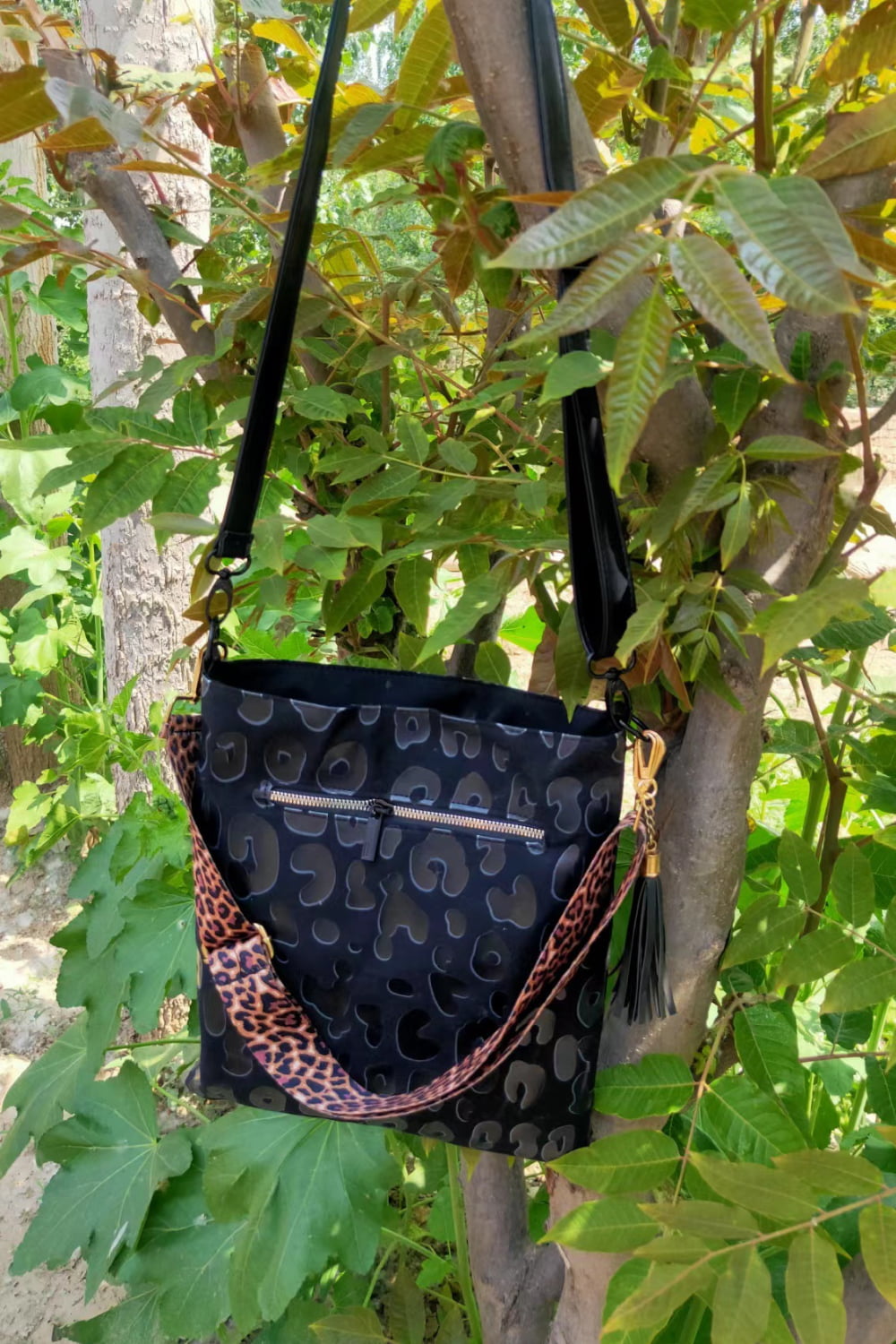Black PU leather shoulder bag with embossed pattern, leopard crossbody strap and tassel