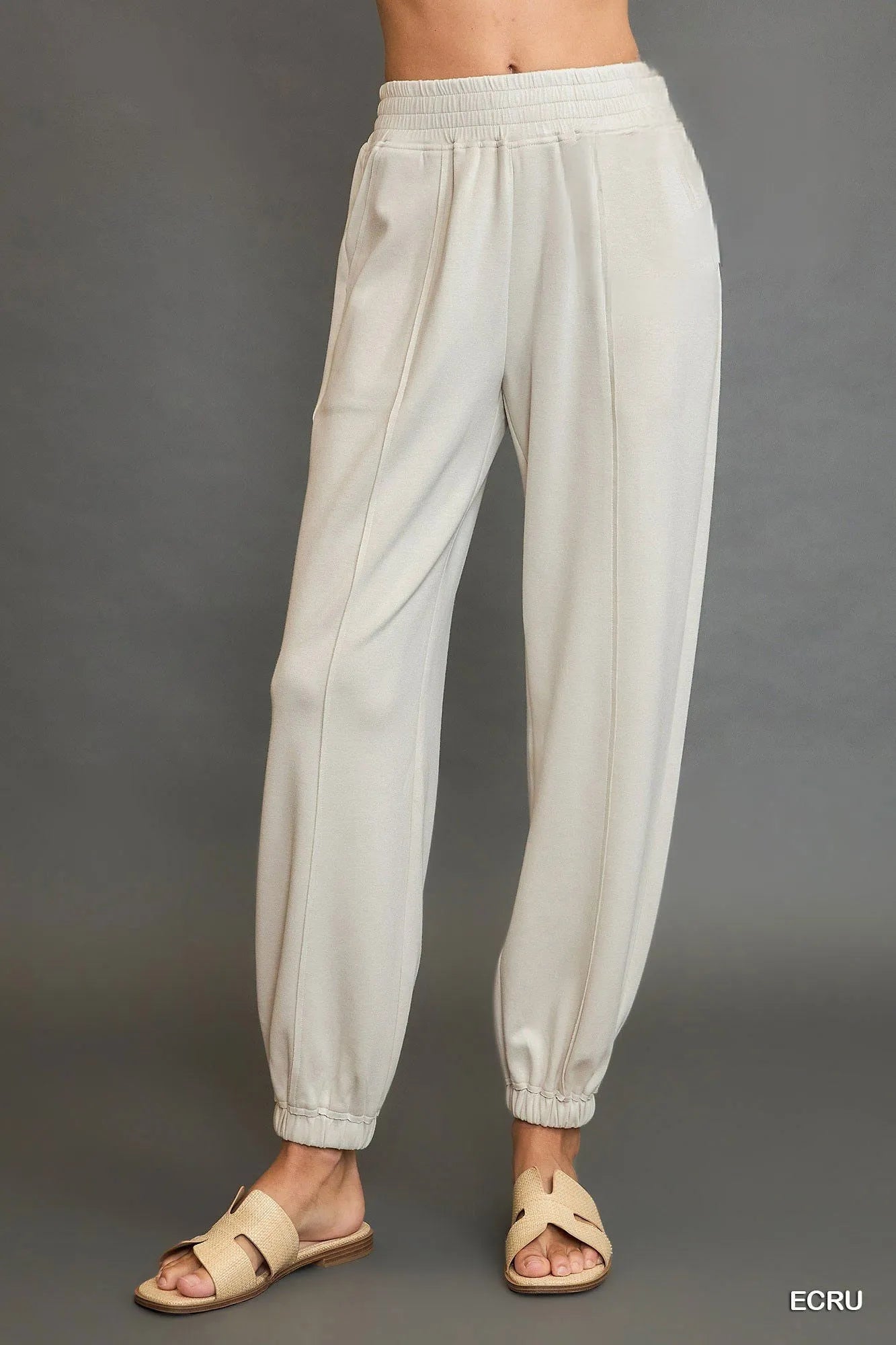 Ecru drawstring jogger pants, side view with front seam detail and elastic cuffs