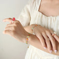 Gold flower bracelet with multicolor enamel blossoms on chain, worn on wrist