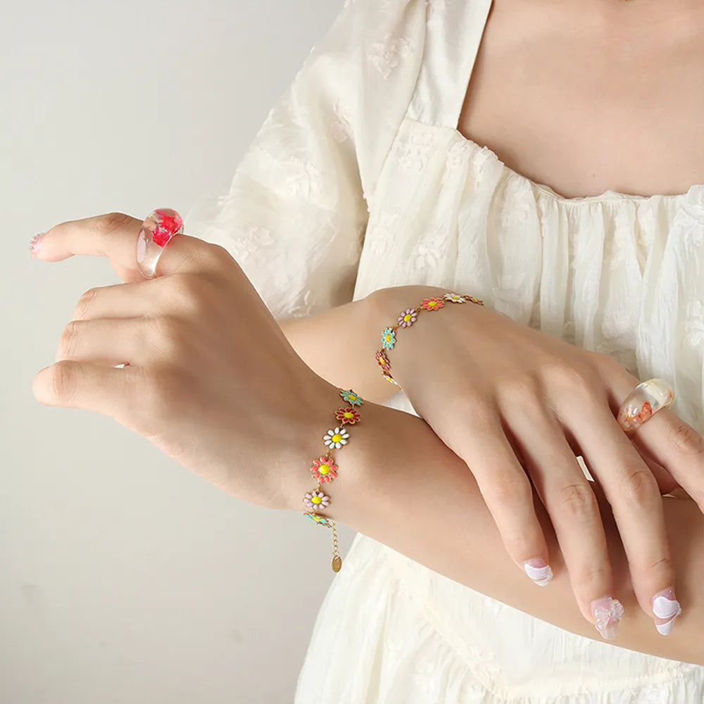 Gold flower bracelet with multicolor enamel blossoms on chain, worn on wrist