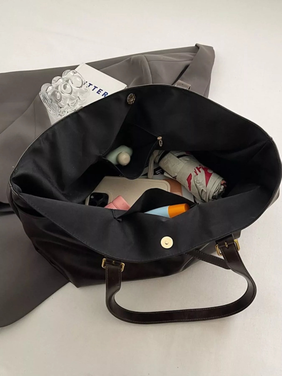 Large vegan leather tote bag, black, open interior with small pockets and items