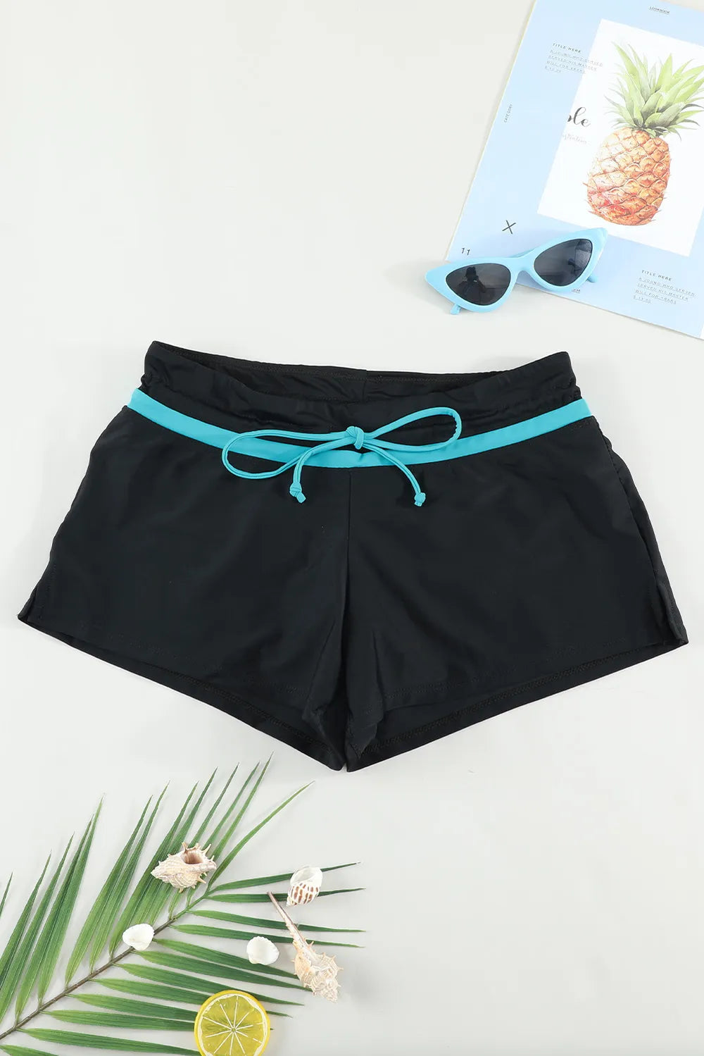 Black swim shorts with turquoise trim and drawstring, flat front view
