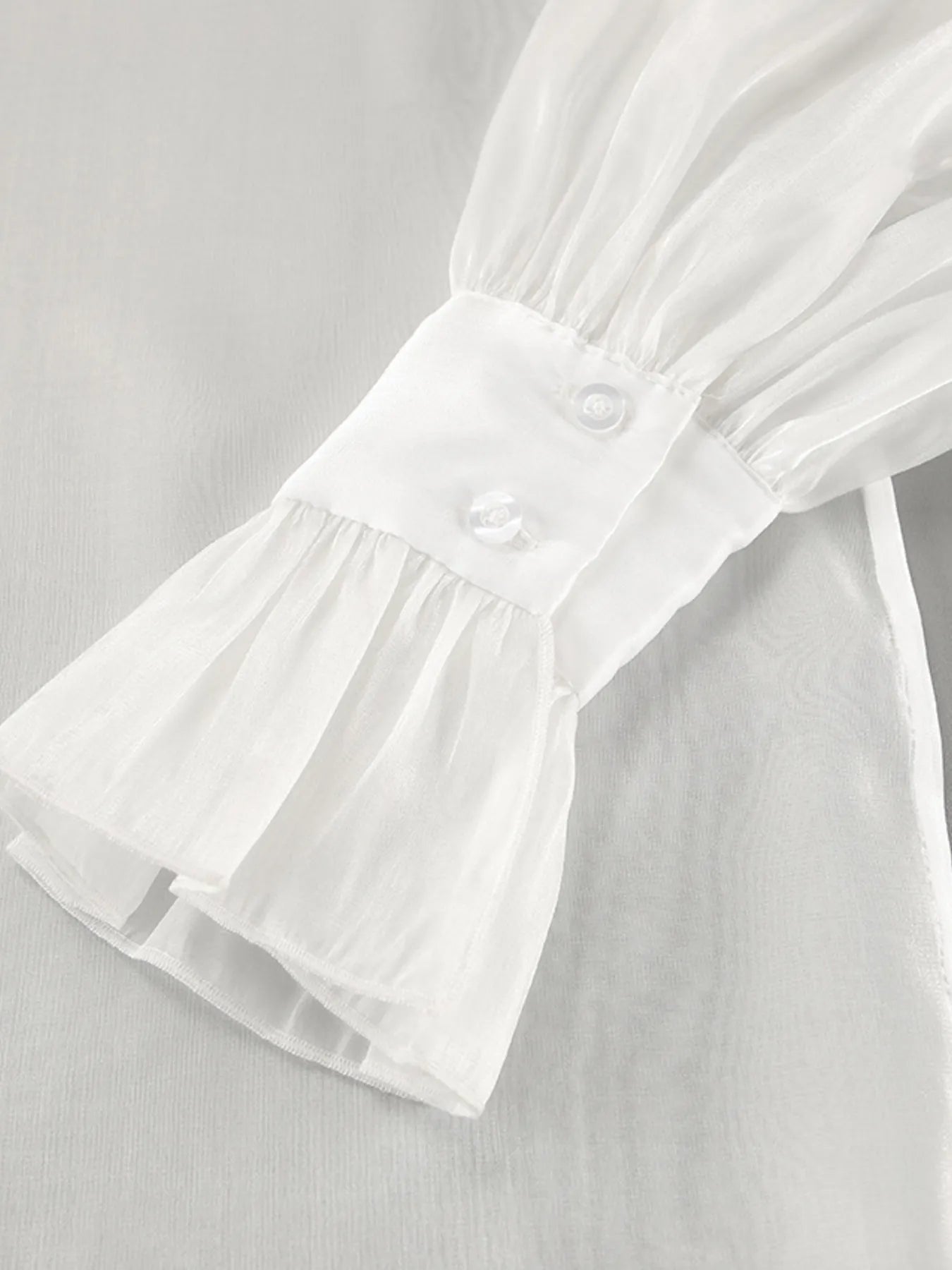 White flounce sleeve shirt sleeve with ruffled cuff and small button detail