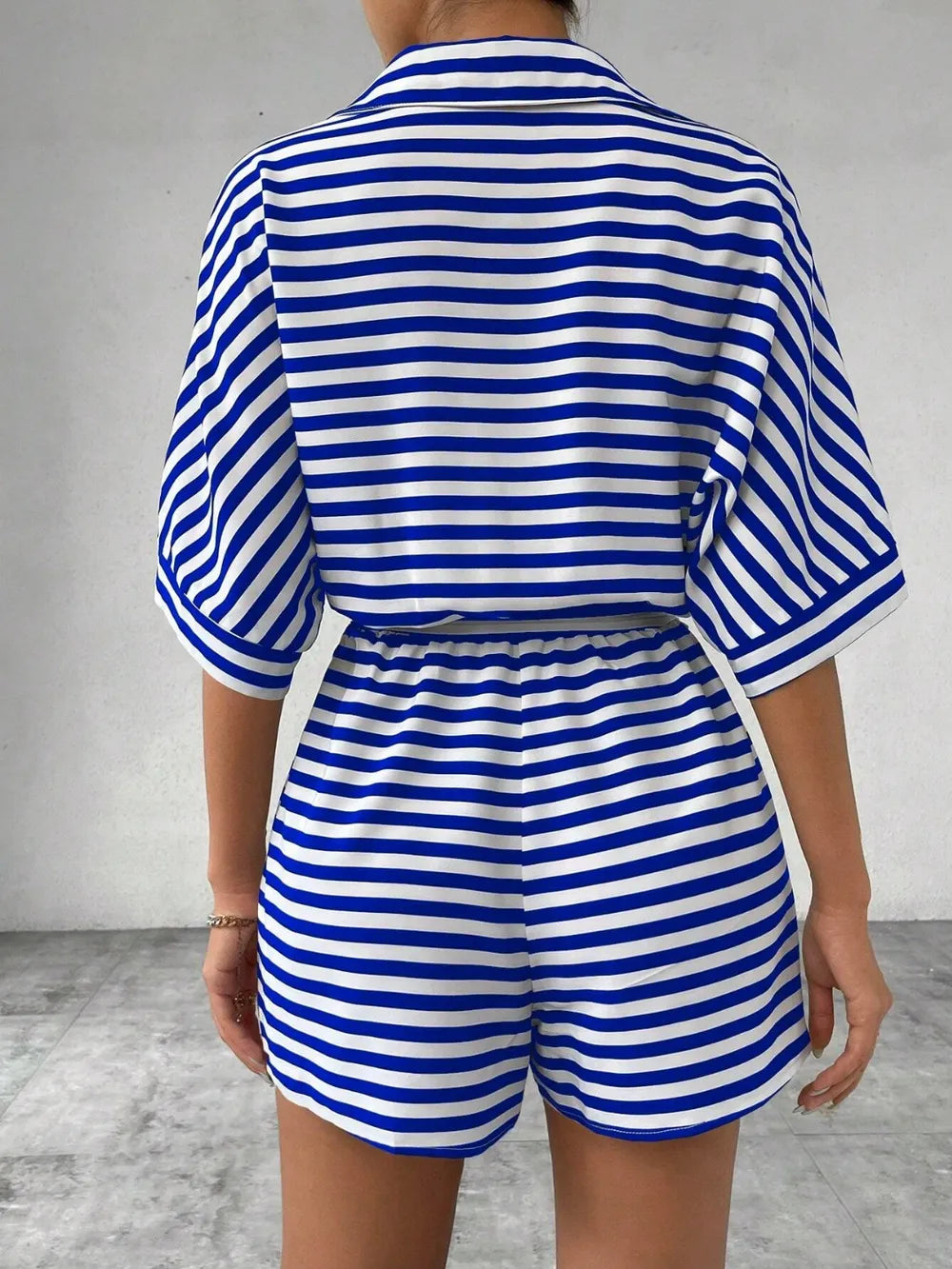 Blue-and-white striped romper with tie waist and half-button top; back view