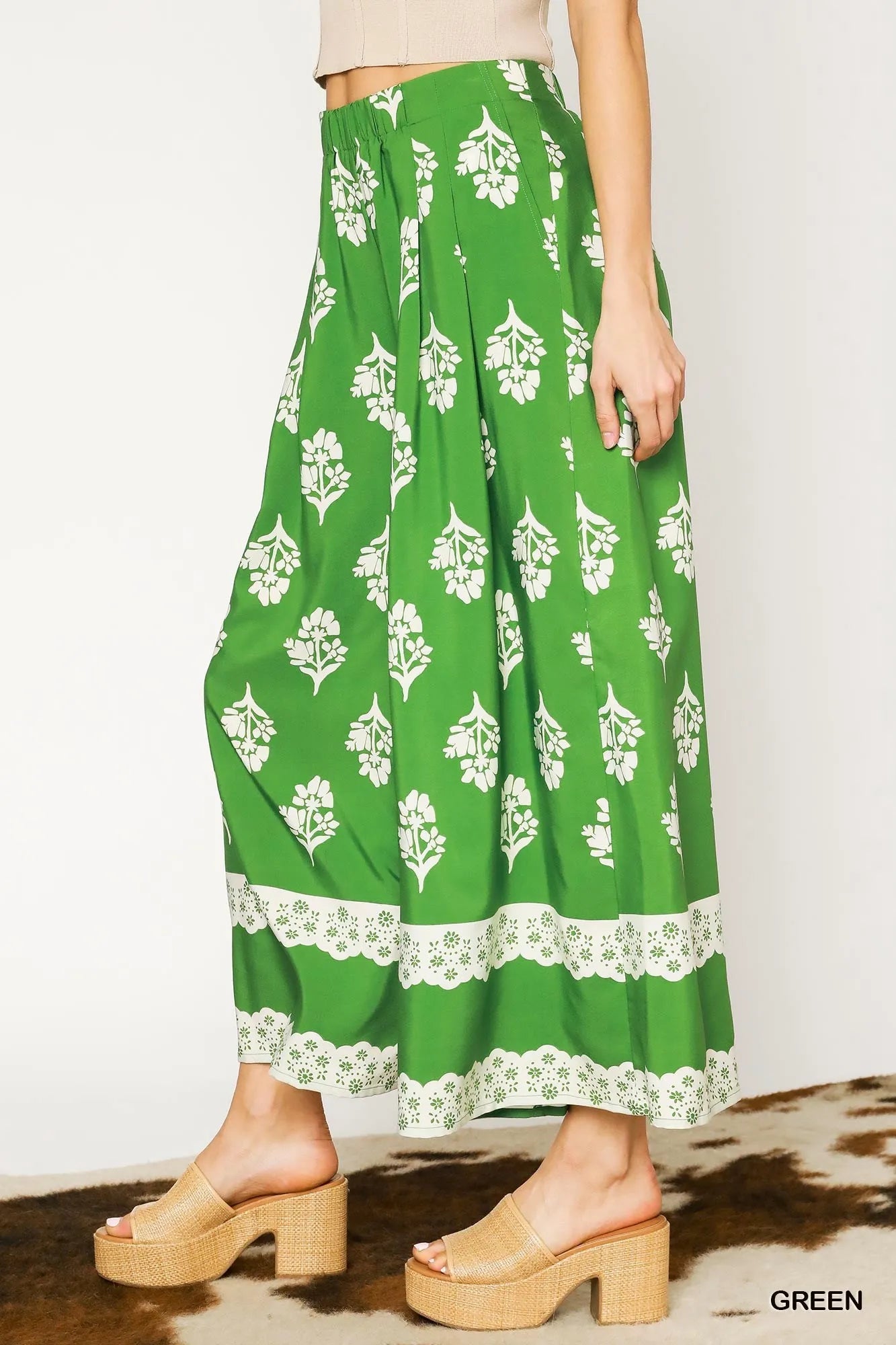Green floral pleated wide-leg pants with white blossoms and lace hem border