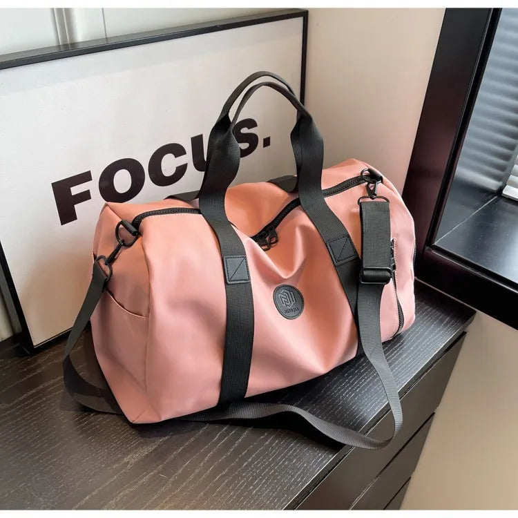 Dusty pink large waterproof duffel bag with black shoulder strap and front pocket zipper