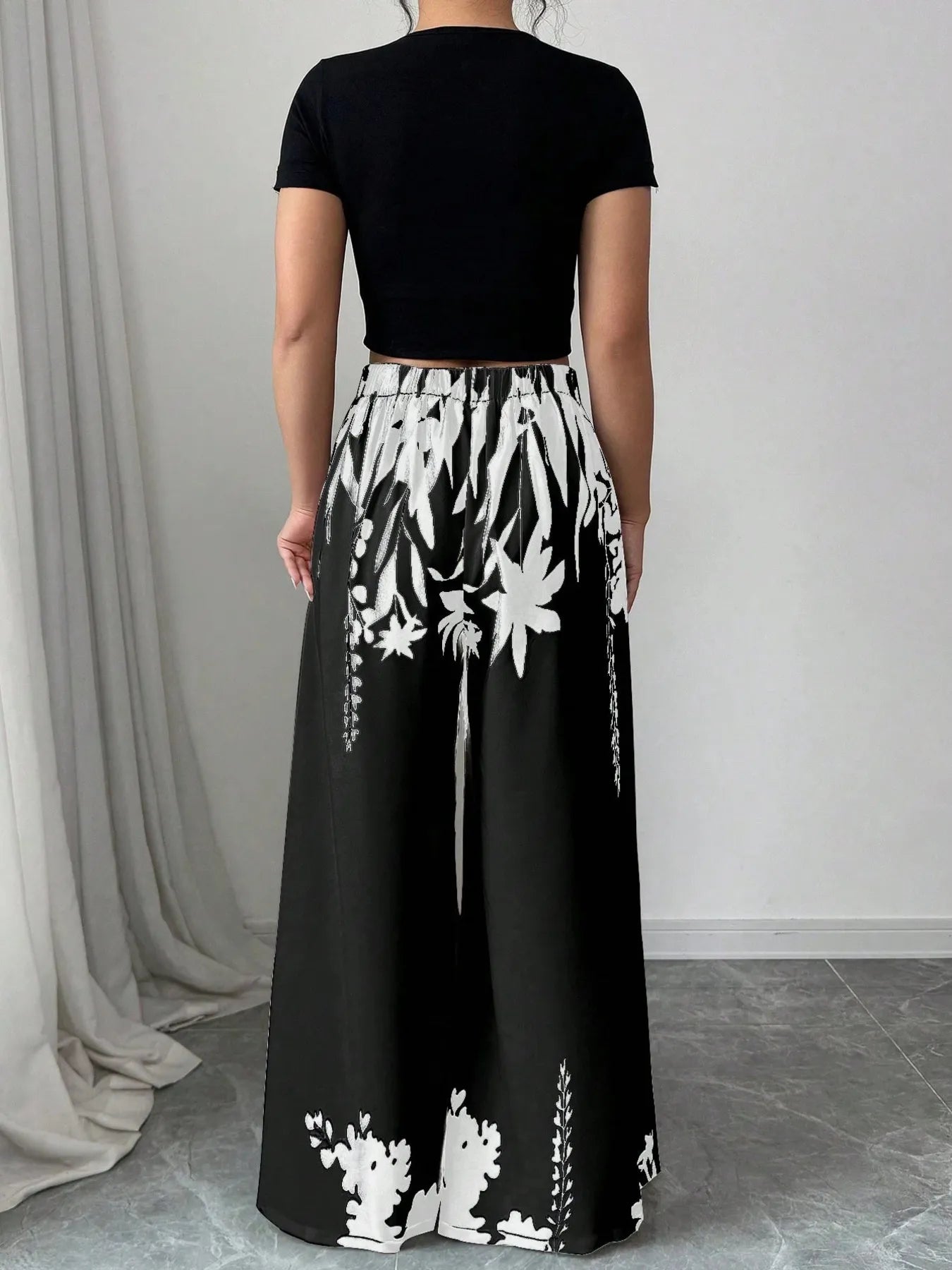 Black and white floral printed wide-leg pants with elastic waist, full back view