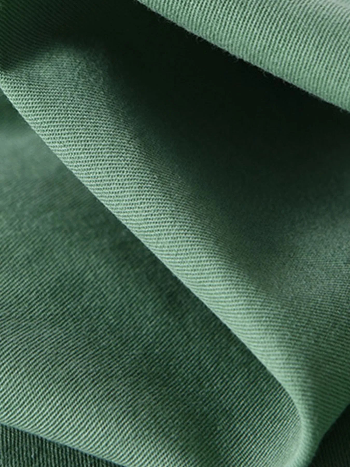 Green shirt fabric close-up showing fine woven texture