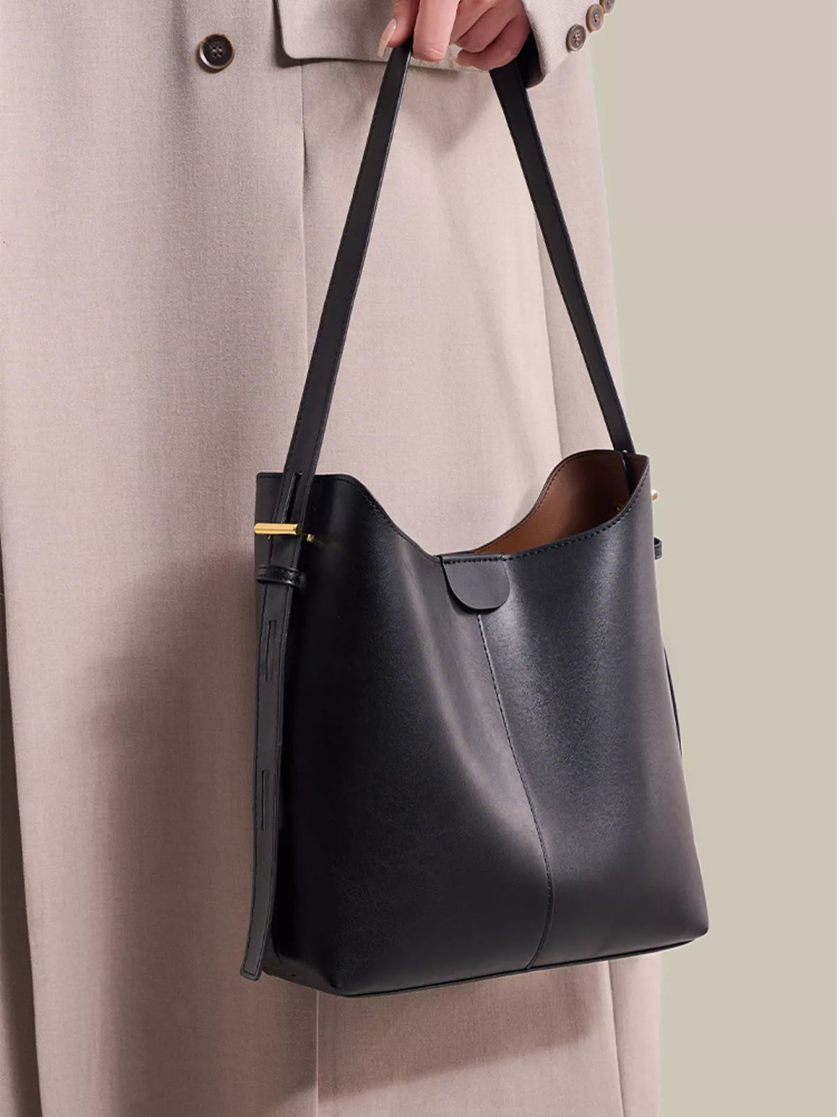 Black medium shoulder bag with adjustable strap, curved flap pocket, and gold hardware